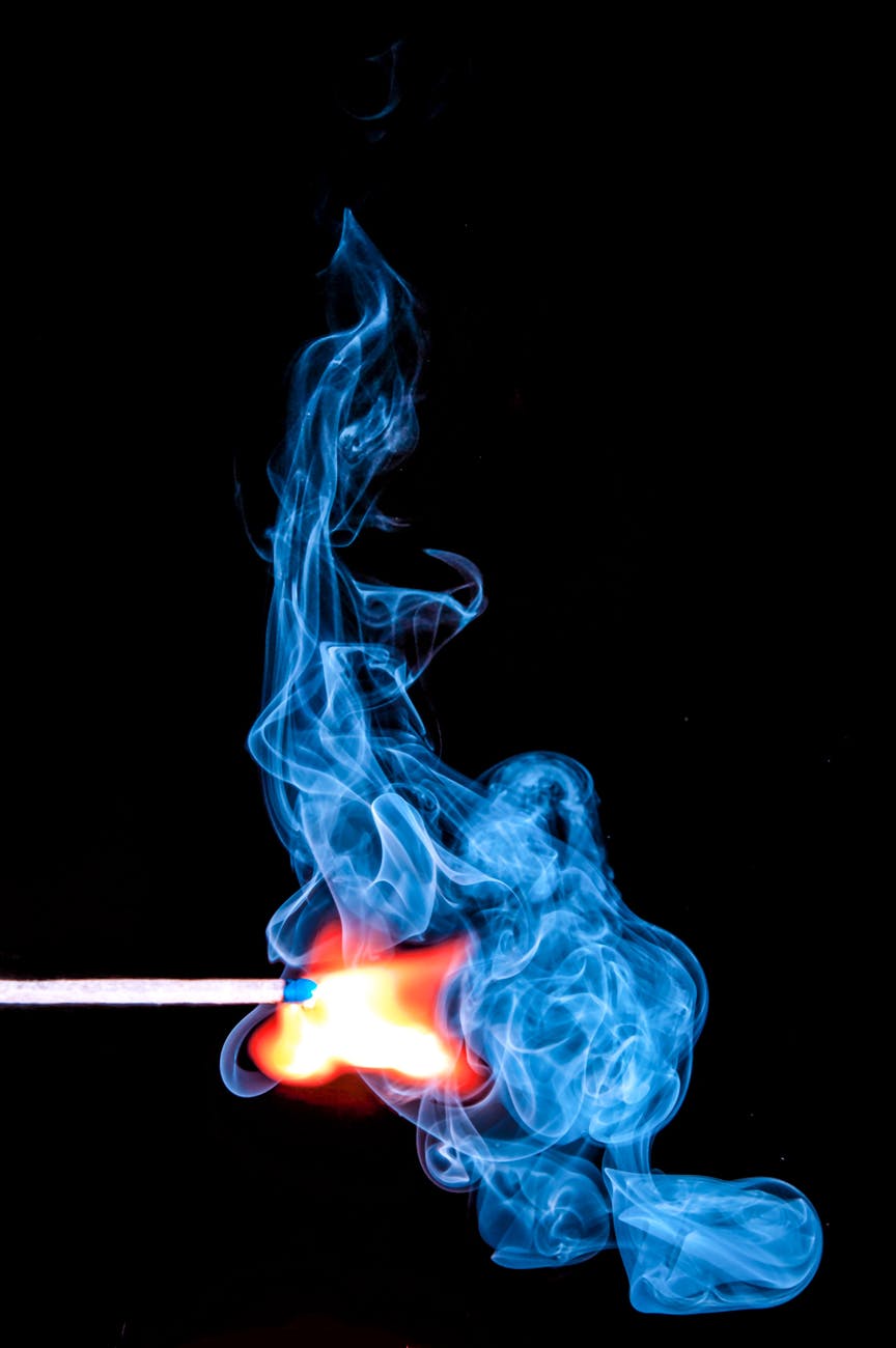 lighted match with smoke on black background