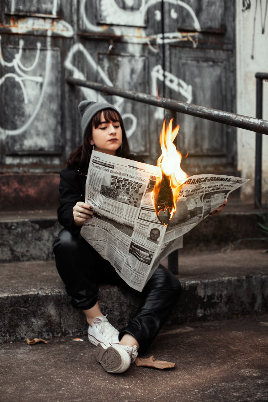 woman holding newspaper while burning